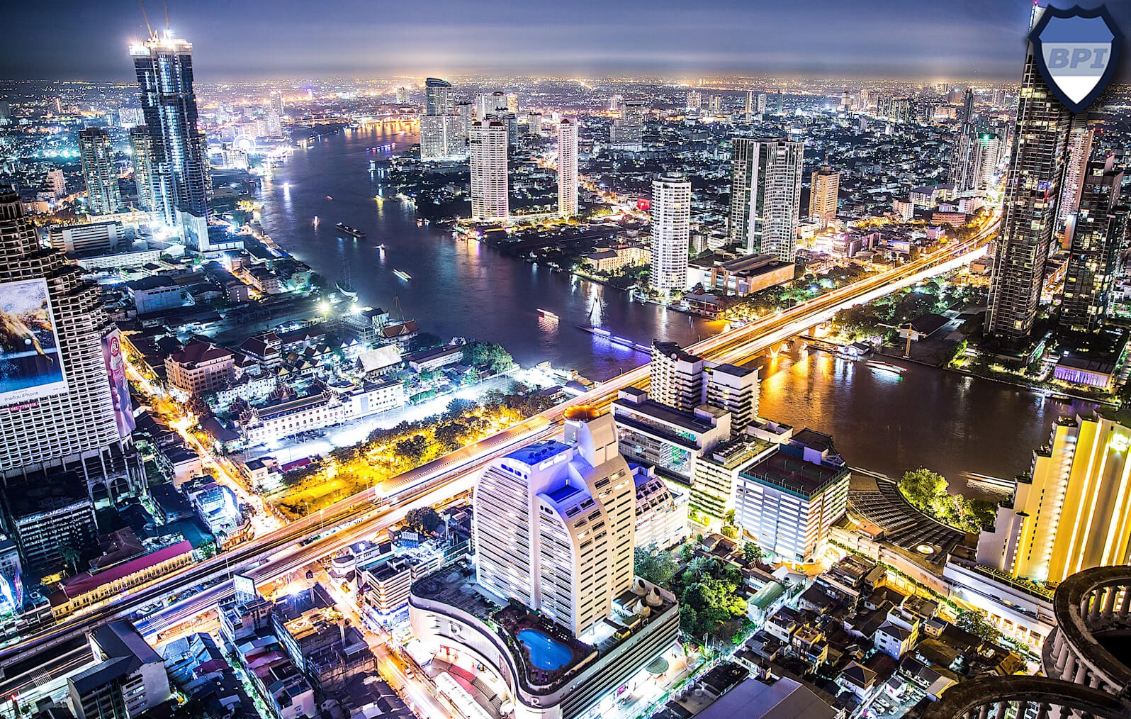 A photo showing buildings surrounding the Chao Phraya River in Bangkok, Thailand at night
