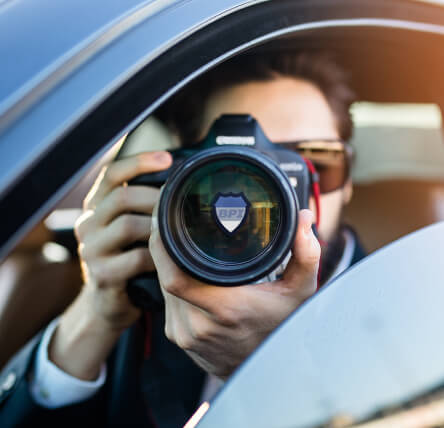 Private investigator wearing a suit and taking photos with a DSLR camera