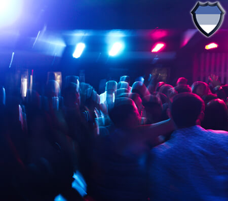 People drinking in a bar underneath red and blue lights