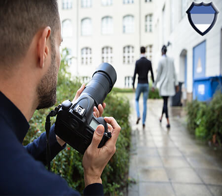 A man with a camera taking photos of a couple that are holding hands