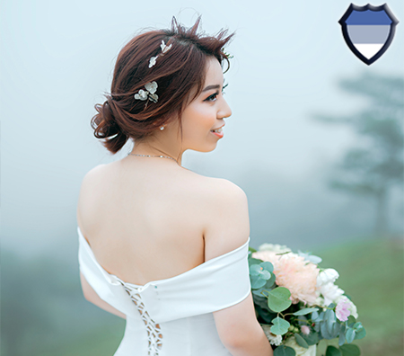 An Asian lady wearing a wedding dress and holding a bouquet of flowers while smiling