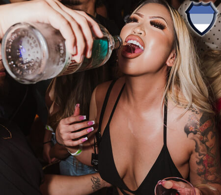 Woman in a tank top drinking alcohol from a bottle