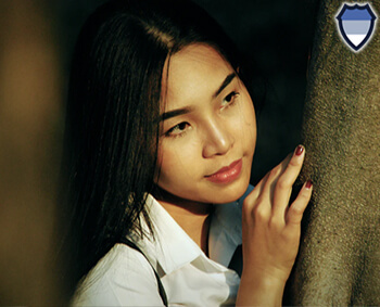 Thai lady leaning on a tree